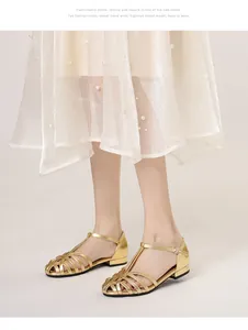 Close-up of golden T-strap woven flat sandals with detailed metallic hollow-out design