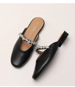Macro view of black pointed-toe mules featuring rhinestone strap and low block heel