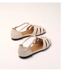 Détail de sandales romaines beige avec bride en T à boucle et design ajouré tressé