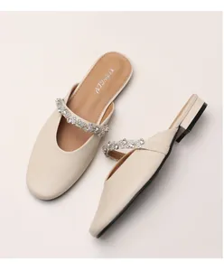 Close-up of cream leather mule with sparkling rhinestone strap and low block heel