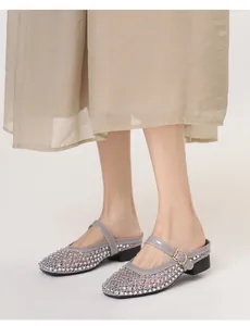 Détail de mules en résille grise avec strass et boucle en métal doré sur le pied