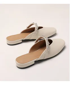 Close-up of beige pointed mules with sparkling rhinestone straps and low block heels
