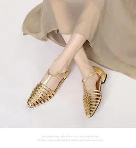 Detail of woven metallic gold flat Roman sandals with buckle ankle strap closure