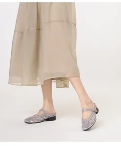 Détail de mules en résille grise ornées de strass brillants et bride dorée