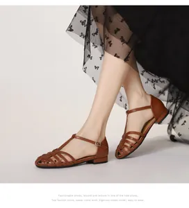 Detail of woven brown leather T-strap sandals featuring cross-strap design and buckle