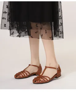 Close-up of caramel brown woven leather sandals featuring a classic T-strap buckle