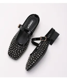 Gros plan de chaussures Mary Jane en cuir verni noir avec clous argentés brillants
