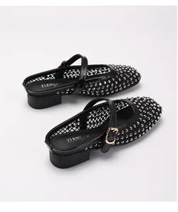 Détail de mules en maille noire avec clous argentés et boucle métallique ajustable