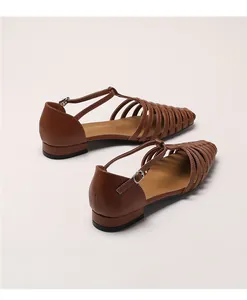 Detailed view of brown T-strap woven gladiator sandals with a metallic buckle closure