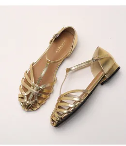 Detail of gold woven cage sandals with T-strap and metallic buckle closure