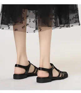 Detail of black woven caged leather sandals with adjustable buckle strap on feet