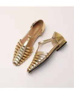 Detailed top view of golden woven cage flat sandals with T-strap buckle and sleek metal finish