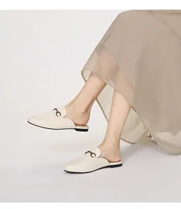 Κοντινό πλάνο σε δερμάτινα mule loafers με μεταλλική αγκράφα φορεμένα από μοντέλο