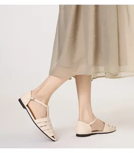Close-up van beige geweven visserssandalen met enkelbandjes en metalen gespen
