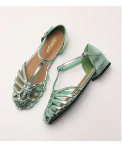 Close-up of light green metallic T-strap woven sandals with adjustable ankle buckle