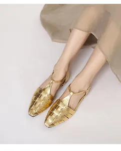 Gedetailleerde foto van gouden geweven platte sandalen met T-strap en gesloten neus