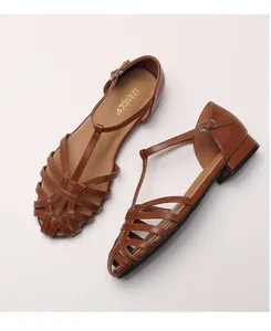 Macro detail of brown woven leather sandals with caged toe and T-strap buckle