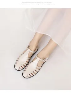 Detail of bohemian hollow woven beige sandals with ankle buckle and black sole