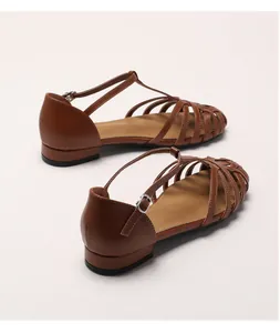 Detail view of brown woven leather sandals with T-strap and buckle closure