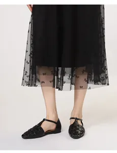 Detail van handgeweven zwarte T-strap sandalen met vierkante neus en vintage textuur