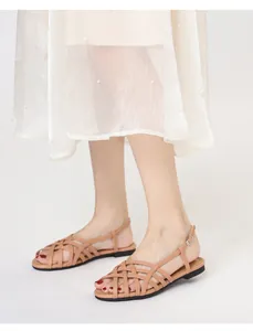 Close-up of khaki woven flat sandals with cross straps and adjustable buckle strap