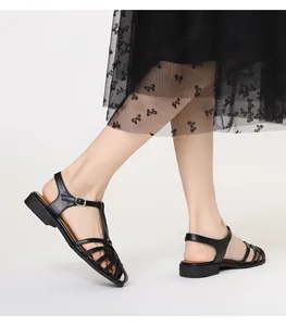 Detail von schwarzen geflochtenen Sandalen mit verstellbarer silberner Schnalle am Knöchel