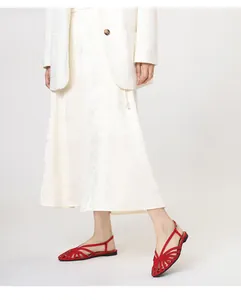 Detail van rode geweven platte sandalen gestyled met een witte gebloemde midi-rok