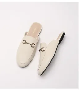 Λεπτομερής όψη κρεμ δερμάτινων mules με vintage χάλκινη μεταλλική αγκράφα αλόγου