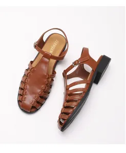 Detailed close-up of brown woven leather fisherman sandals with an adjustable ankle strap