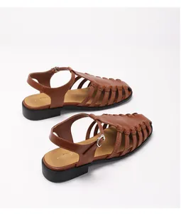 Macro view of brown woven leather fisherman sandals with adjustable metal buckle strap