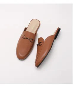 Λεπτομερής λήψη καφέ δερμάτινων mules με vintage χάλκινη αγκράφα τύπου horsebit