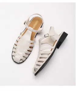Detail view of woven hollow pointed-toe sandals with adjustable ankle strap and low heel
