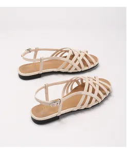 Close-up of beige woven straps and adjustable buckle detail on women's flat sandals