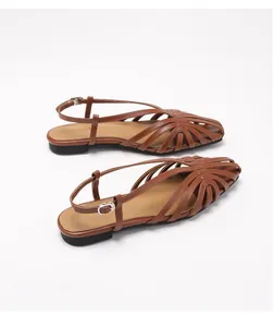 Detail van bruine geweven lederen sandalen met verstelbare zilveren metalen gesp