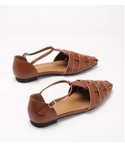 Detailopname van bruine gevlochten platte sandalen met T-bandje en vintage gesp