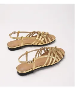 Detail of gold metallic woven straps and adjustable buckle on women's flat sandals