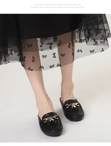 Primo piano di eleganti sabot in pelle nera con fibbia dorata e dettaglio a nappa