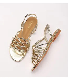 Detail of gold woven strappy Roman sandals featuring metallic finish and buckle closure