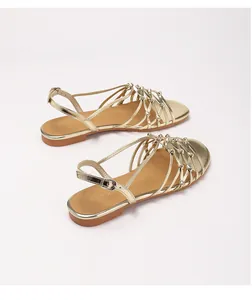 Close-up of golden handmade woven thin straps and diamond-shaped knots on flat Roman sandals