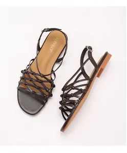 Detail of woven brown strappy Roman sandals with adjustable ankle buckle and gold lettering