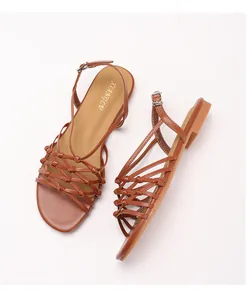 Detailed view of brown woven straps and metal buckle on flat Roman sandals
