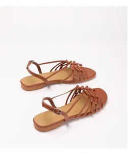 Detail of woven brown leather straps and adjustable buckle on flat Roman sandals
