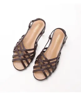 Close-up of deep brown woven strap sandals featuring a gold brand logo on the soft insole