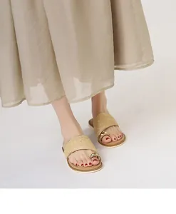 Detail des champagnergoldenen Webriemens und Zehenrings an flachen Sandalen
