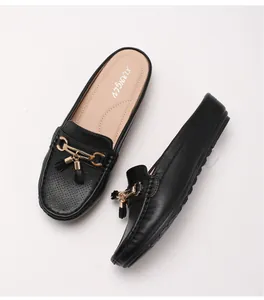 Dettaglio di sabot in pelle nera con fibbia dorata e design traforato