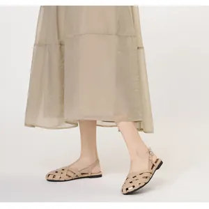 Detalle de sandalias planas tejidas en color beige con hebilla de metal ajustable fija