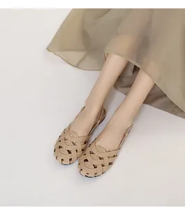 Sandalias planas trenzadas beige de mujer en cuero con un vestido ligero