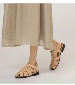 Detail von beigen geflochtenen Ledersandalen mit Riemchen und flacher schwarzer Sohle