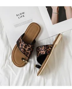 Detail der flachen Leoparden-Sandale mit goldenem Zehenring und Magazin-Hintergrund