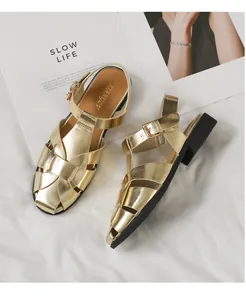 Nahaufnahme der goldenen geflochtenen Textur und Schnalle an Retro Römer Sandalen